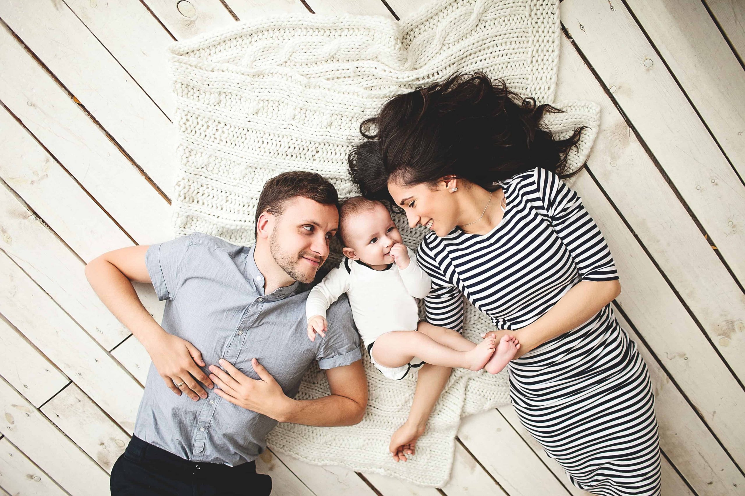 Happy Family snuggling on blanket with infant baby