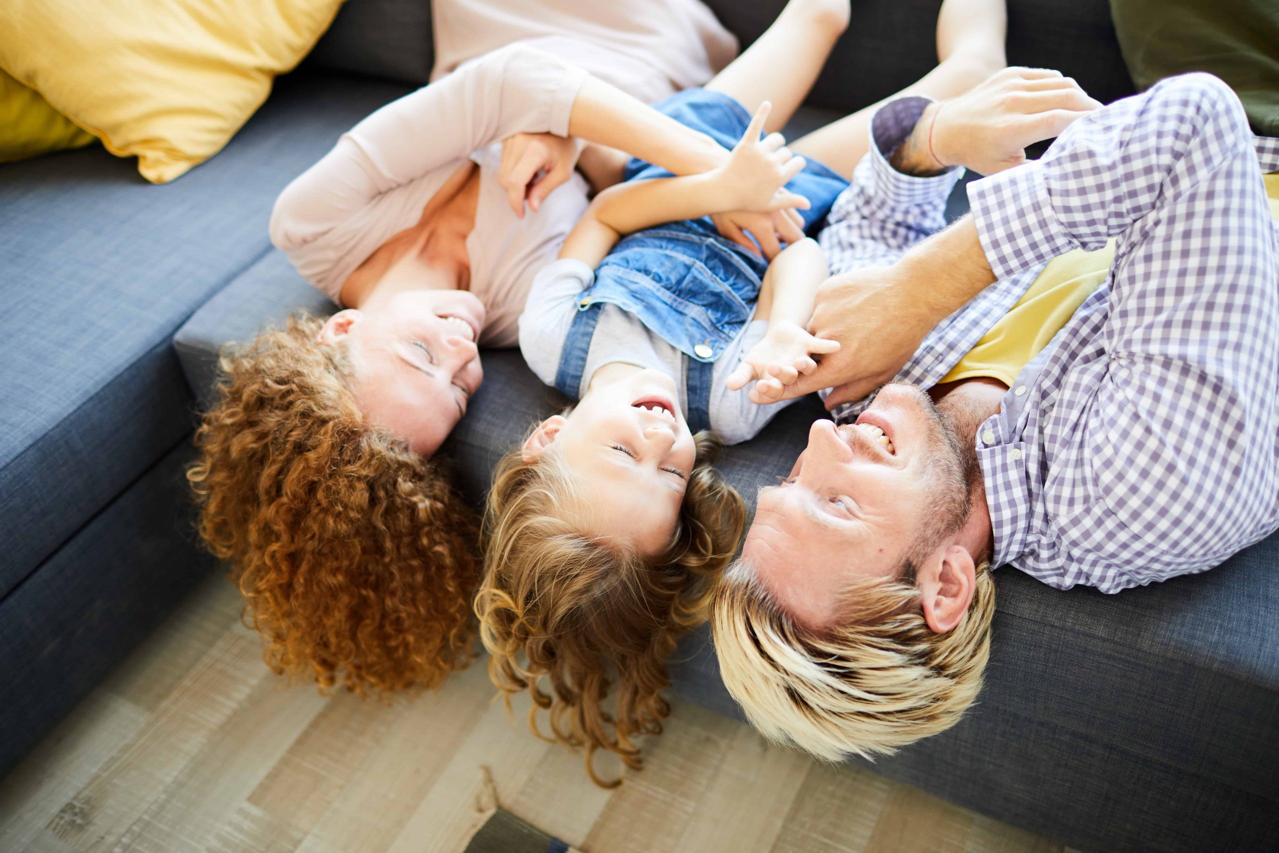 Happy Adoptive family wrestling around on couch