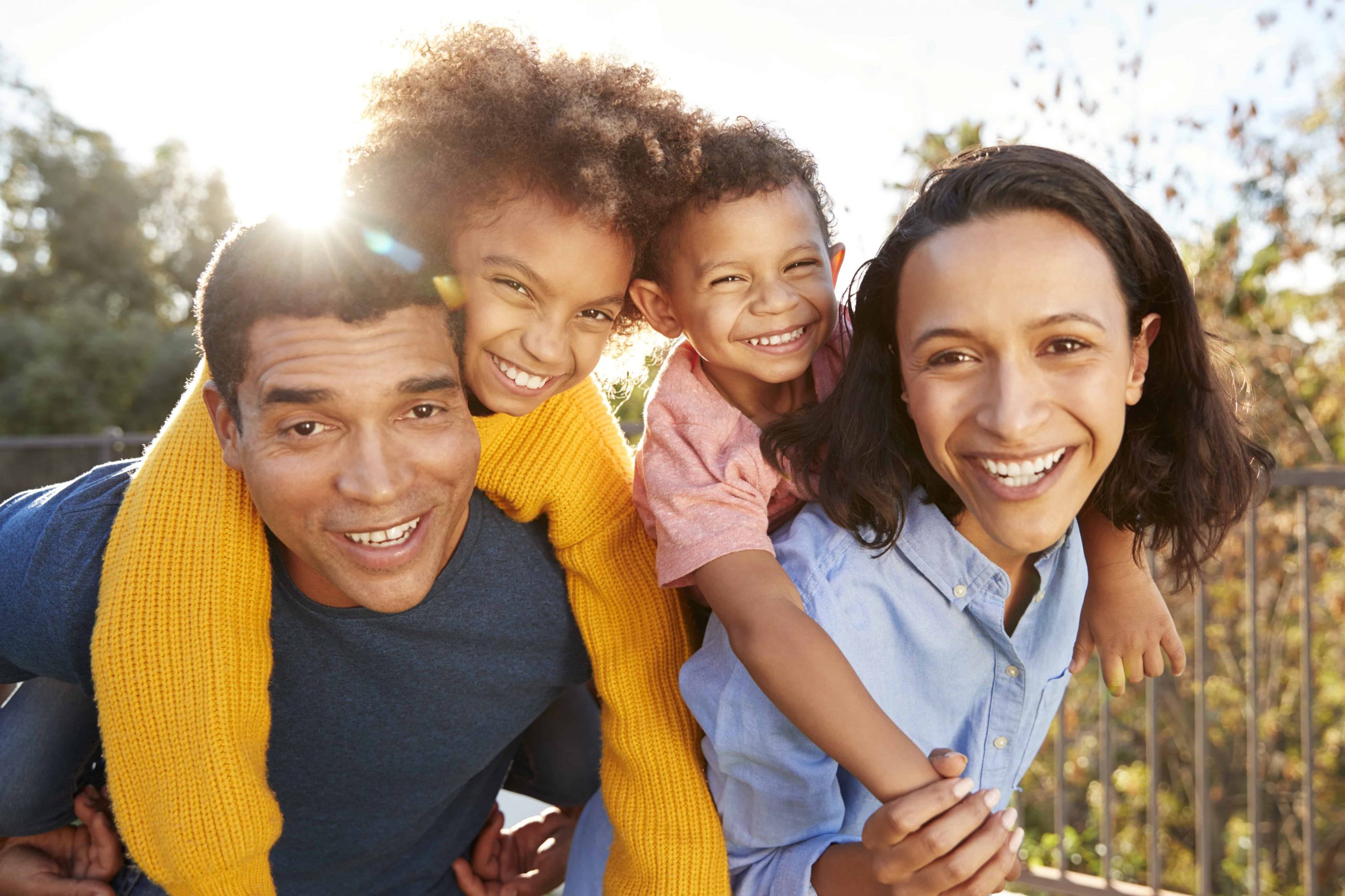 adoptive Family with young kids doing piggy back rides